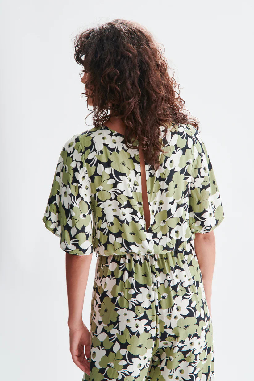 Detail of open slit in back of chic floral belted jumpsuit featuring oversized green botanical print and flowy short sleeves for effortless styling.