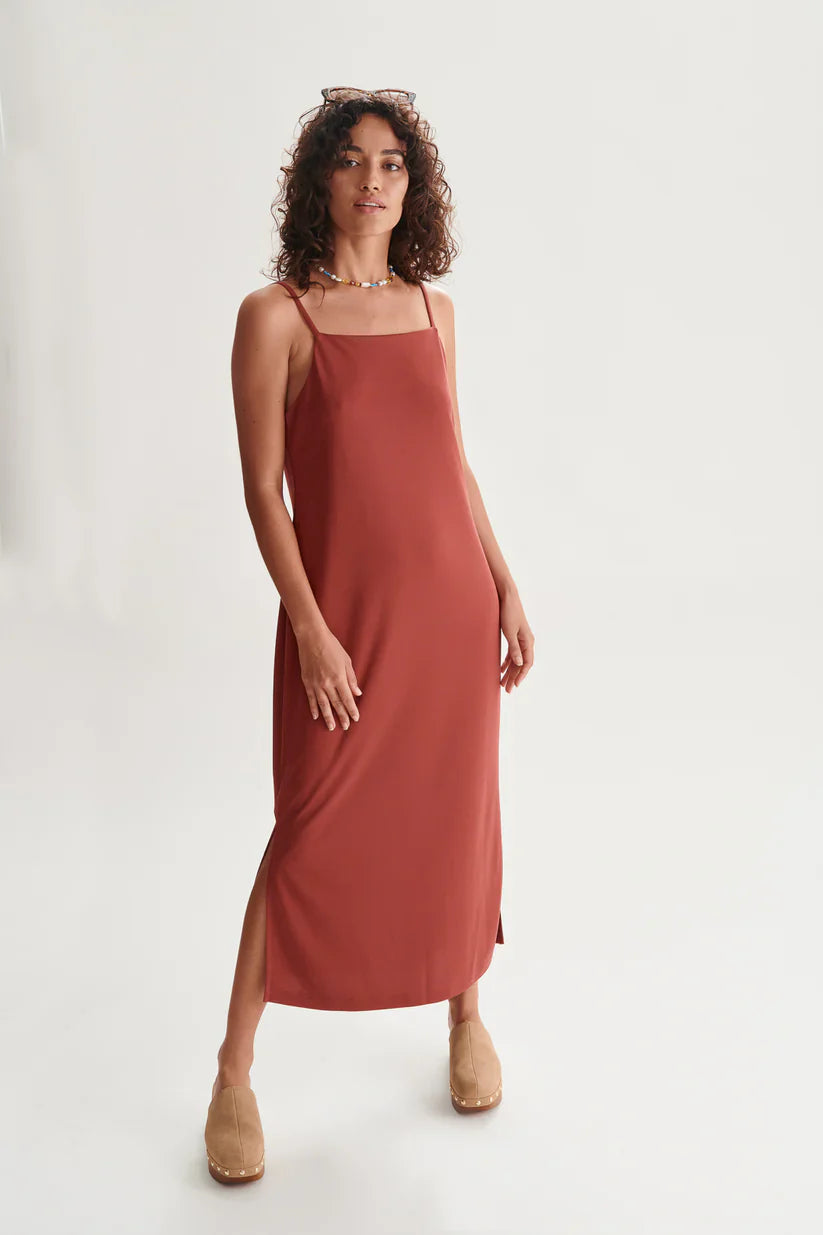 Trendy terracotta slip midi dress with side slit detail and lightweight fluid silhouette for vacation outfits.