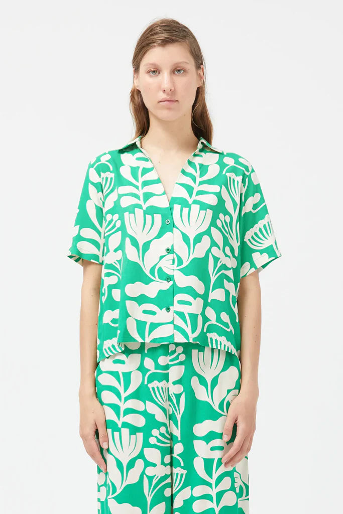 Emerald green short sleeve blouse with bold white botanical print and effortless vacation-ready styling.