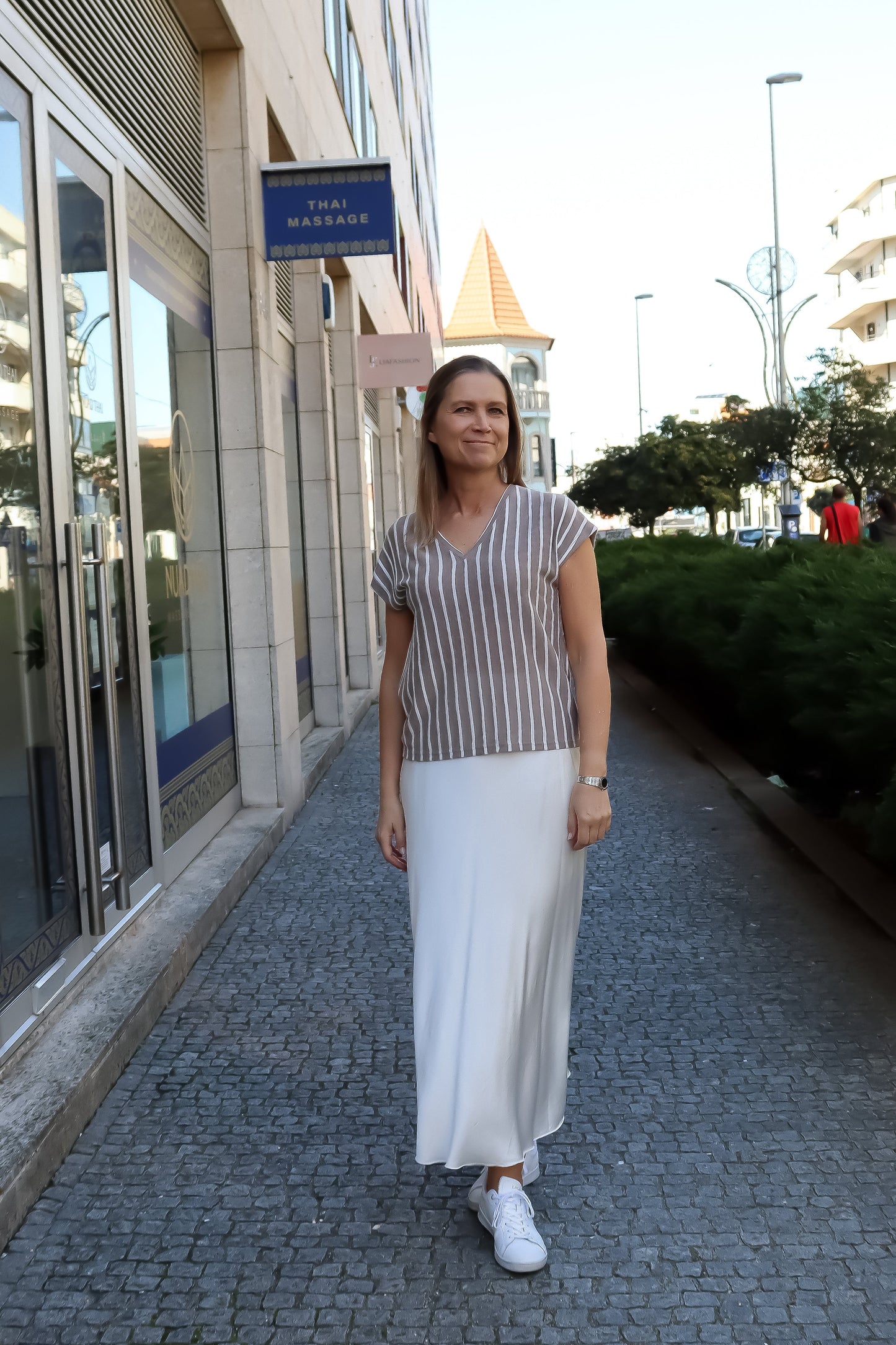 Soft taupe striped V-neck top with breathable knit texture and elevated women’s casualwear styling.