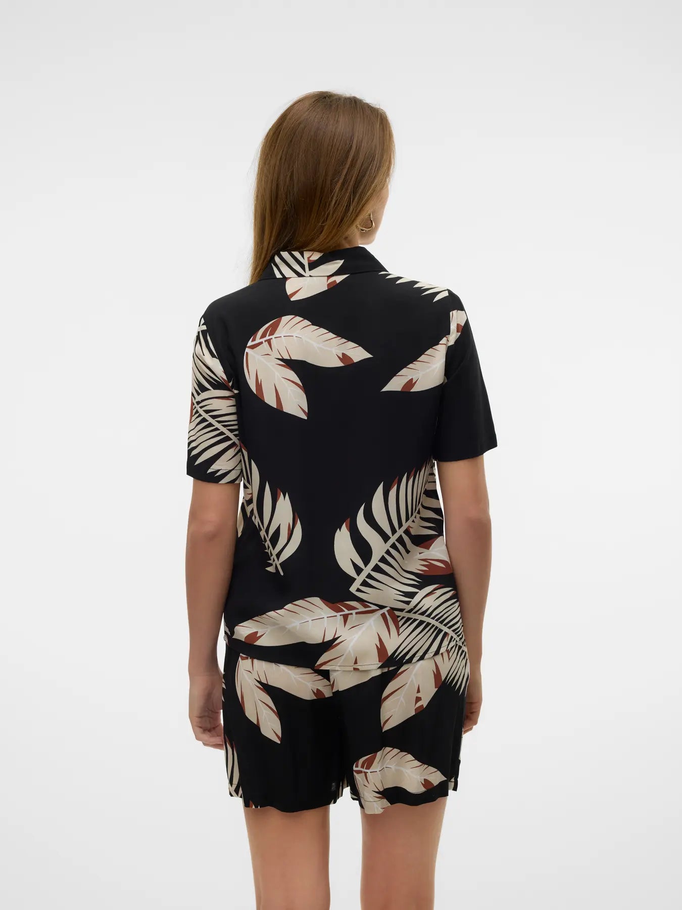 Back view of contemporary palm leaf blouse in black and cream with chic island-inspired fashion vibe.