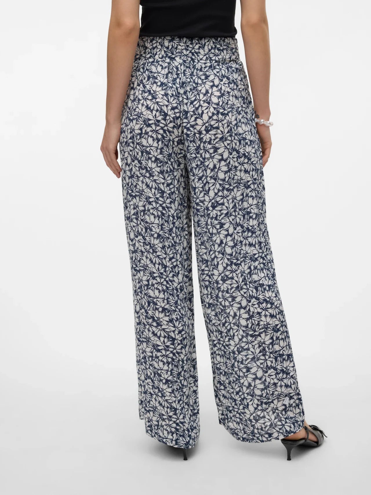 Back view of Chic black and white floral trousers with relaxed fit and polished minimalist fashion appeal.