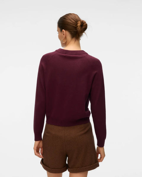 Women's deep plum crew neck sweater with long sleeves and decorative metallic gold button accents.