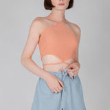 Peach ribbed halter crop top with crisscross neckline and cutout waist detail for women.