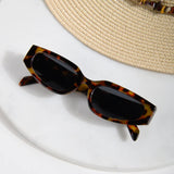 Women's vintage-inspired rectangle sunglasses with a polished tortoise finish and sleek dark lenses.