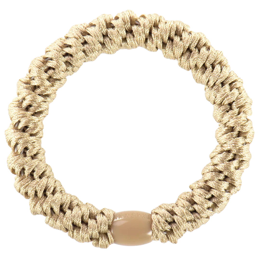 Artisan-inspired woven smooth hair tie with textured braid pattern and earthy green tones for laid-back fashion looks.