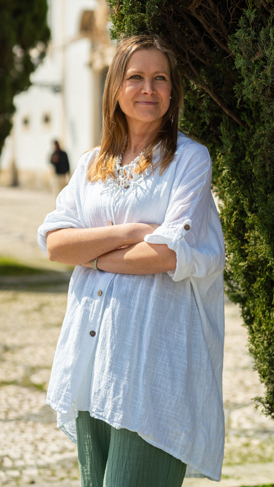 Fashion-forward relaxed linen blouse dress with rolled sleeves and minimalist summer styling.