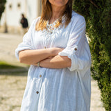Fashion-forward relaxed linen blouse dress with rolled sleeves and minimalist summer styling.