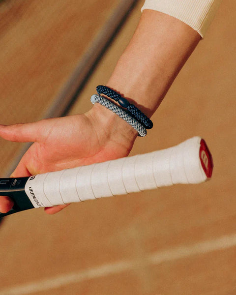 KKNEKKI Navy.  Close up of Knekki hair ties.  Tennis player holding a racket with silver and navy blue Knekki's on the wrist.