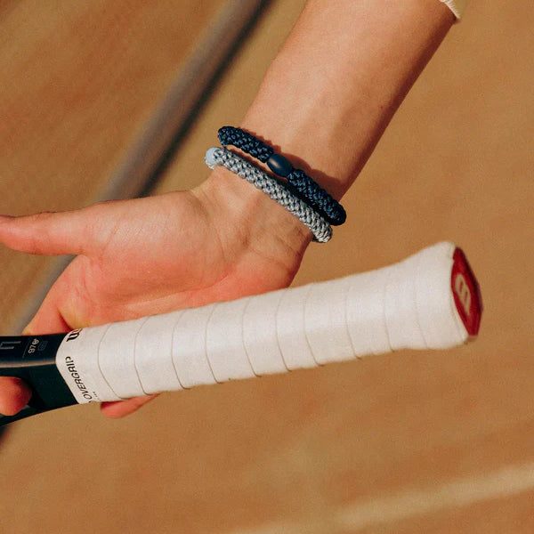 KKNEKKI Navy.  Close up of Knekki hair ties.  Tennis player holding a racket with silver and navy blue Knekki's on the wrist.