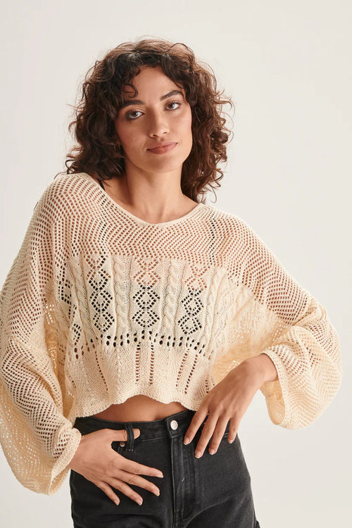 Contemporary open-knit jumper with cable stitch detail and oversized sleeves for chic layering and vacation-ready styling.