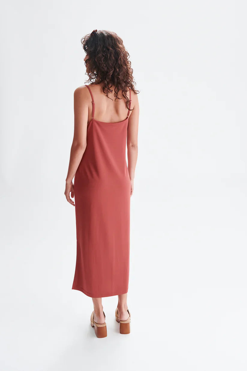 Chic rust midi dress featuring delicate straps and relaxed draped fit for modern resort wear styling.