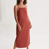 Trendy terracotta slip midi dress with side slit detail and lightweight fluid silhouette for vacation outfits.