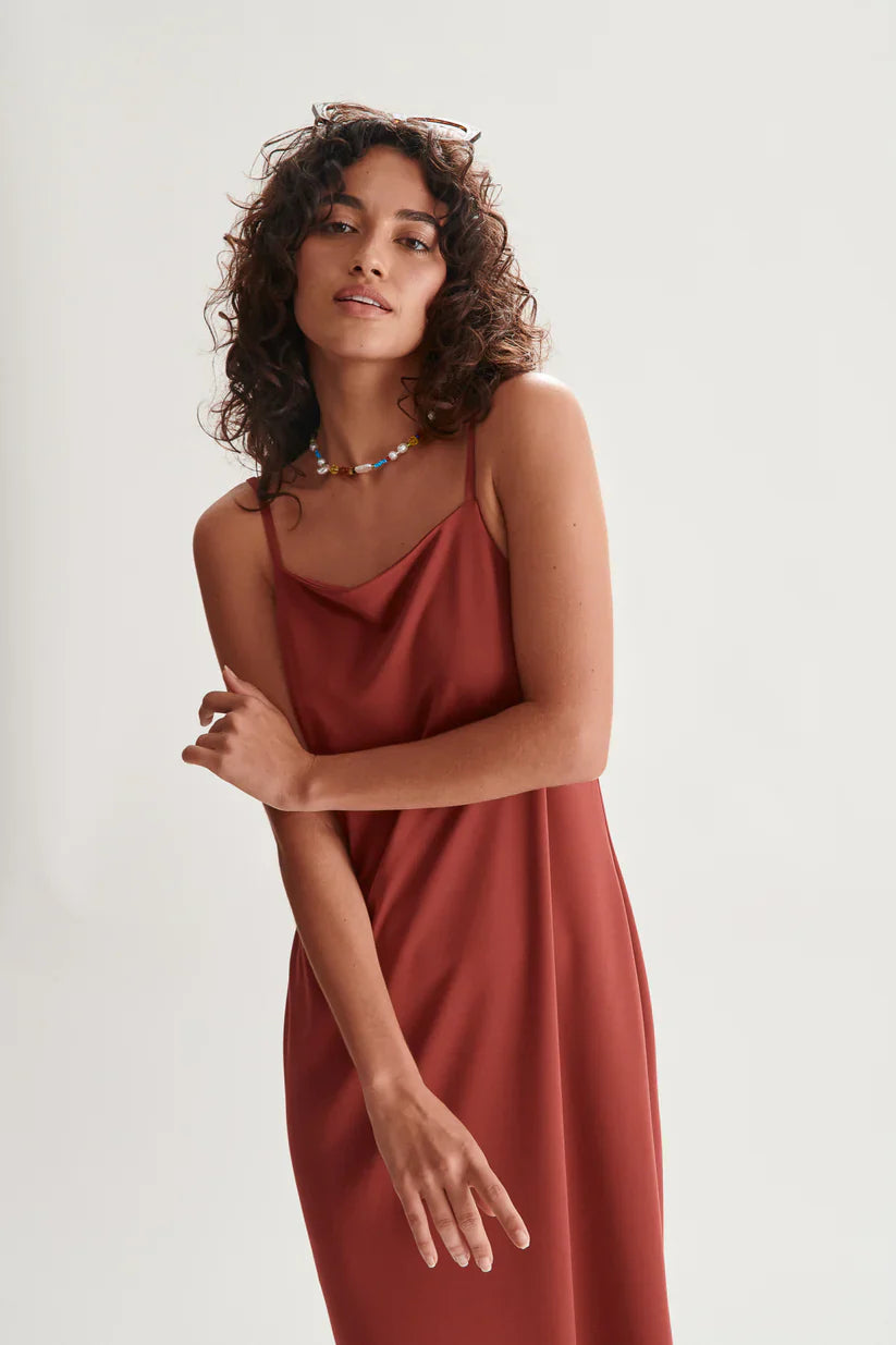 Contemporary terracotta slip dress with delicate straps and effortless relaxed vacation-ready styling.