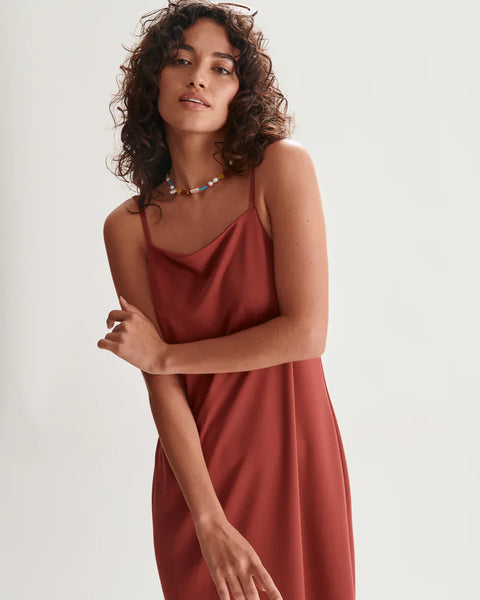 Contemporary terracotta slip dress with delicate straps and effortless relaxed vacation-ready styling.