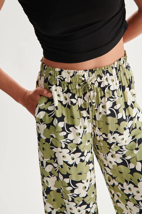 Women’s flowy floral trousers featuring oversized olive flower pattern and comfortable elastic waistband design.