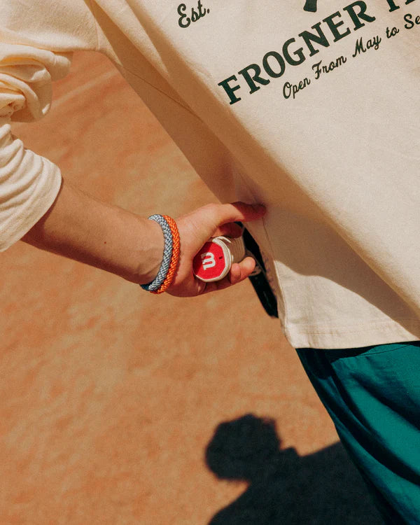 Close up of tennis player with two Knekki hair ties on his wrist, holding a tennis racket.