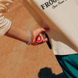 Close up of tennis player with two Knekki hair ties on his wrist, holding a tennis racket.