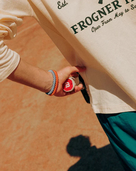 Close up of tennis player with two Knekki hair ties on his wrist, holding a tennis racket.