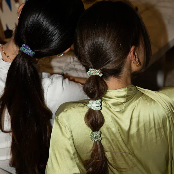 Two women with their hair tied back with scrunchies, one with multiple hair ties on her long hair.  Hair design with Knekki hair ties.