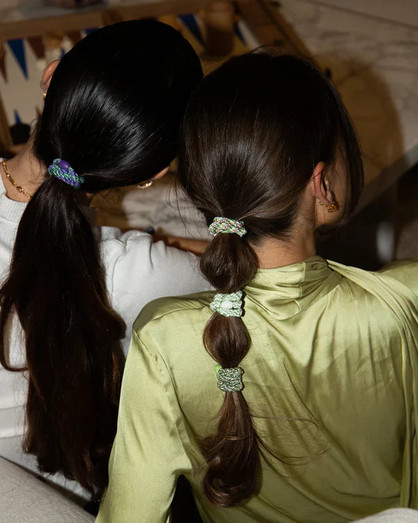 Two women with their hair tied back with scrunchies, one with multiple hair ties on her long hair.  Hair design with Knekki hair ties.