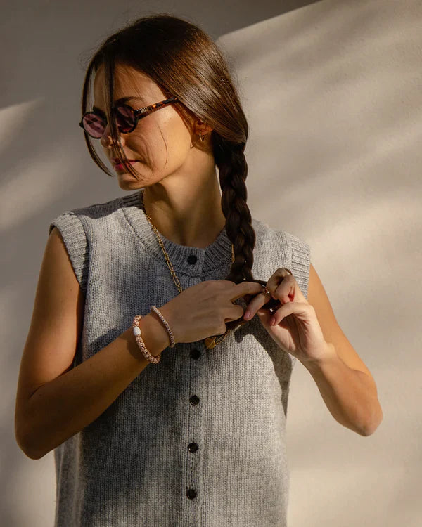 KKNEKKI Rosegold Glitter.  Woman  braiding her hair, wearing her Knekki hair tie as a bracelet.  Scrunchy as jewelry.
