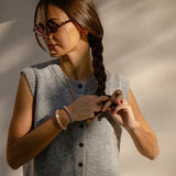 KKNEKKI Rosegold Glitter.  Woman  braiding her hair, wearing her Knekki hair tie as a bracelet.  Scrunchy as jewelry.