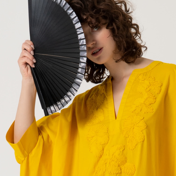 Elegant women’s handheld fan in black with minimalist striped trim and contemporary resort-inspired aesthetic.