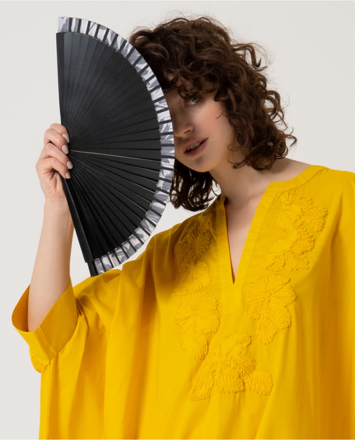 Elegant women’s handheld fan in black with minimalist striped trim and contemporary resort-inspired aesthetic.