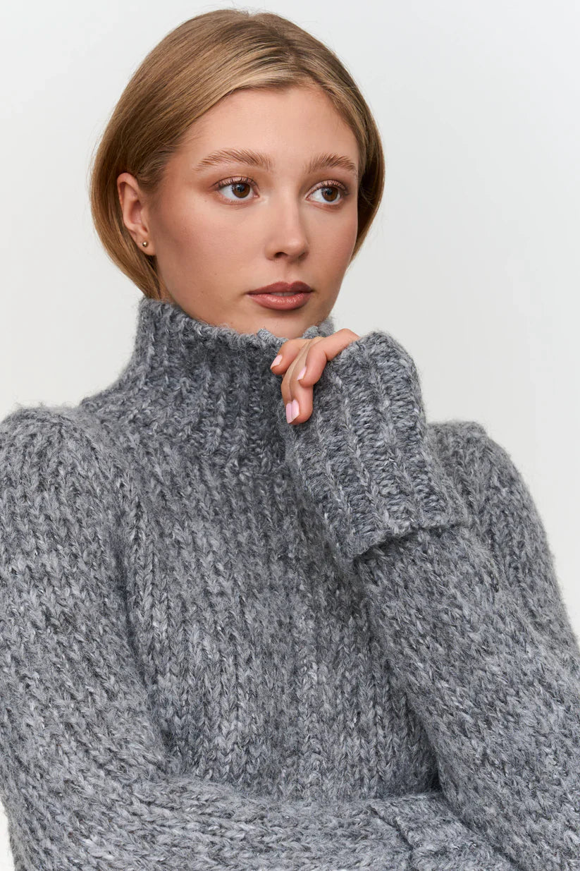 Women’s chunky gray knit sweater with high turtleneck collar, perfect for warm fall and winter layering.