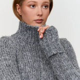 Women’s chunky gray knit sweater with high turtleneck collar, perfect for warm fall and winter layering.