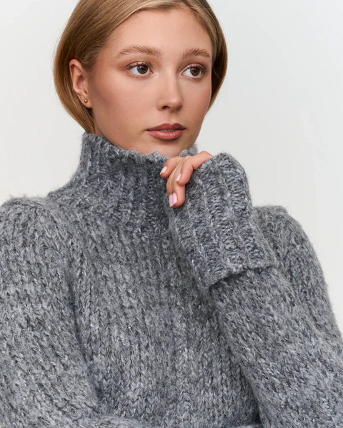 Women’s chunky gray knit sweater with high turtleneck collar, perfect for warm fall and winter layering.