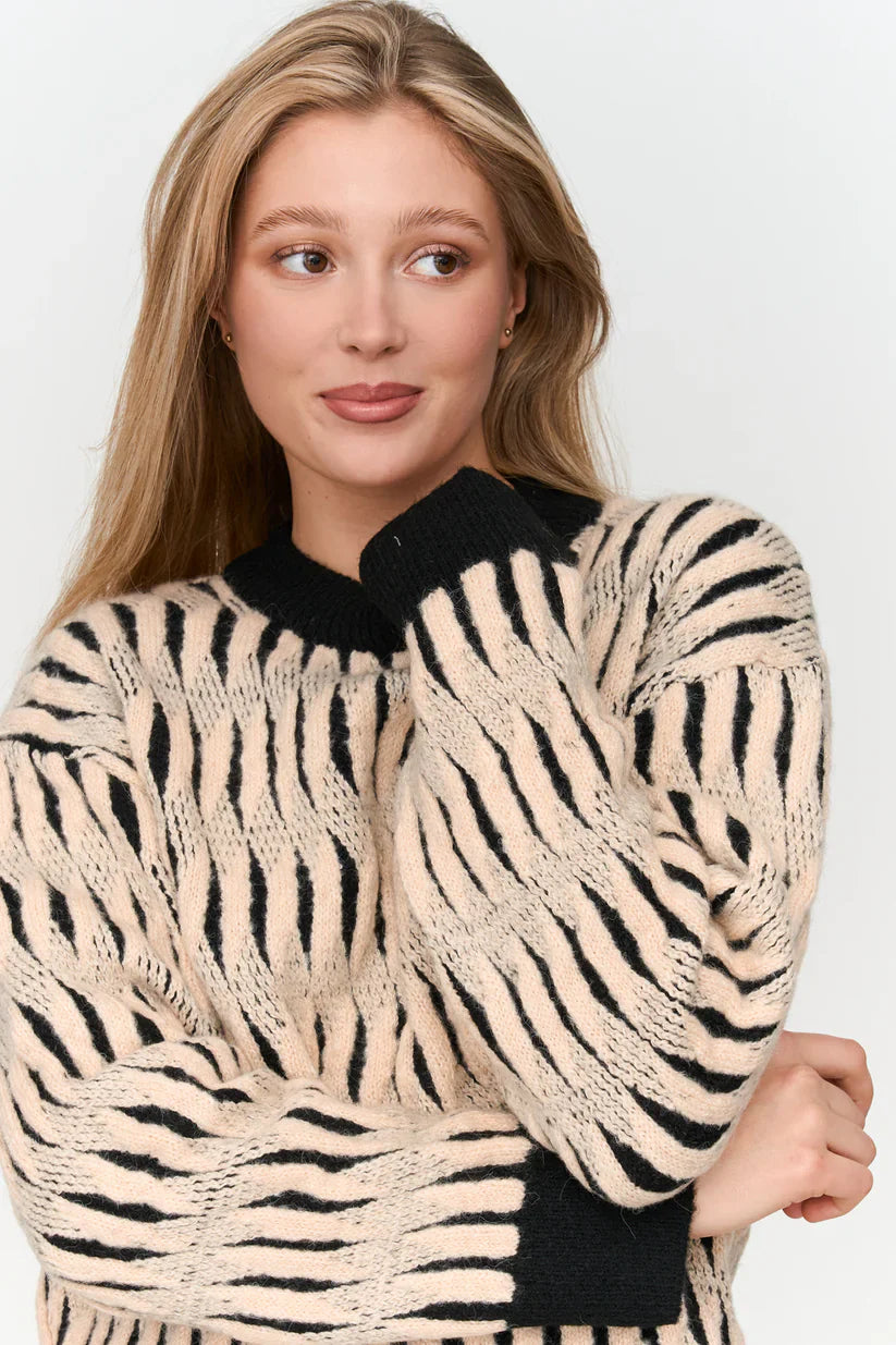Women’s oversized zebra stripe sweater with black contrast neckline and bold cream animal print design.