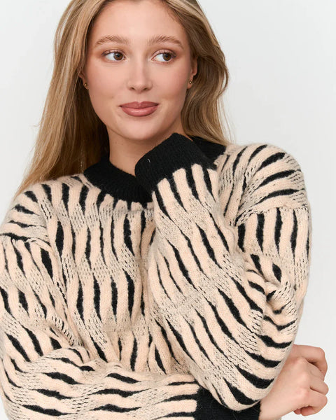 Women’s oversized zebra stripe sweater with black contrast neckline and bold cream animal print design.