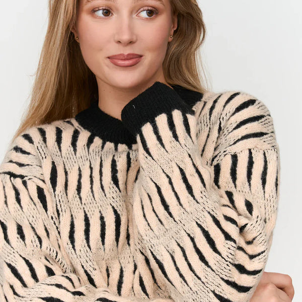 Women’s oversized zebra stripe sweater with black contrast neckline and bold cream animal print design.
