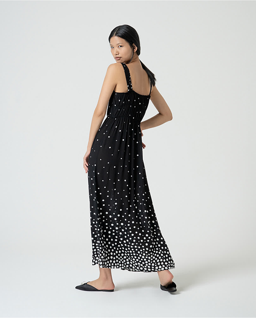 Elegant black maxi dress with white dot pattern and relaxed vacation-ready boho chic styling.