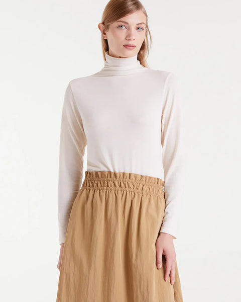Women’s ivory fitted turtleneck top for layering under blazers and sweaters or styling with trousers, skirts, and jeans.
