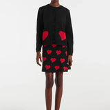 Black A-line mini skirt for women with all-over red heart pattern for playful preppy, party, and going-out outfits.