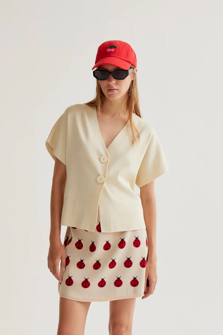 Women's minimalist cream V-neck top with statement buttons, short sleeves and contemporary tailored design for effortless sophistication.
