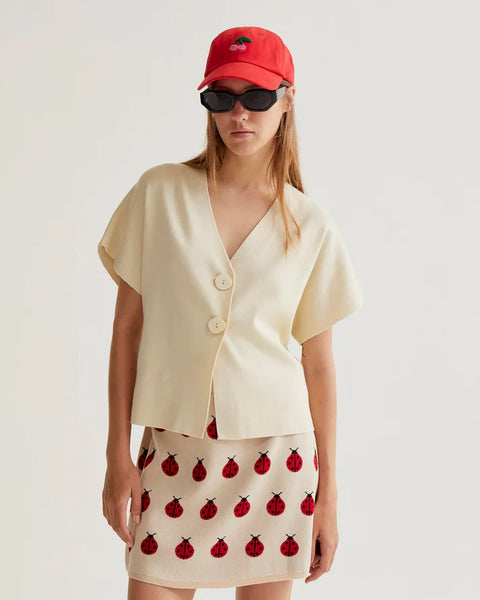 Women's minimalist cream V-neck top with statement buttons, short sleeves and contemporary tailored design for effortless sophistication.