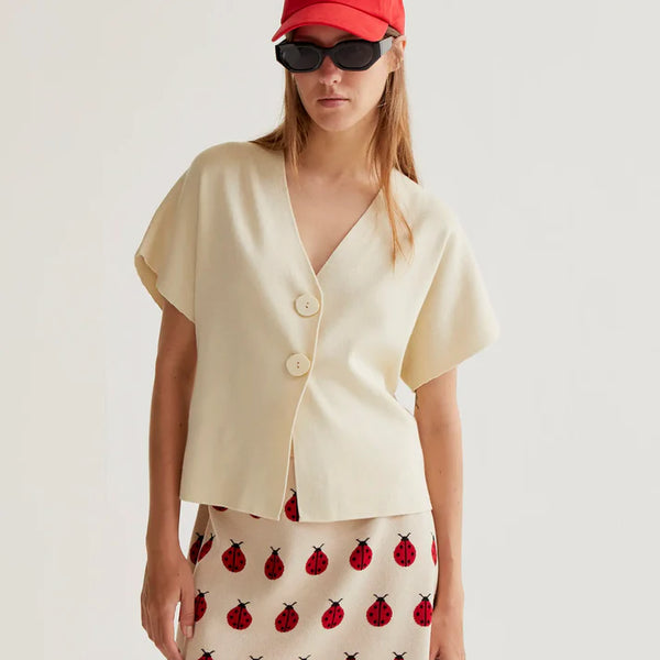 Women's minimalist cream V-neck top with statement buttons, short sleeves and contemporary tailored design for effortless sophistication.