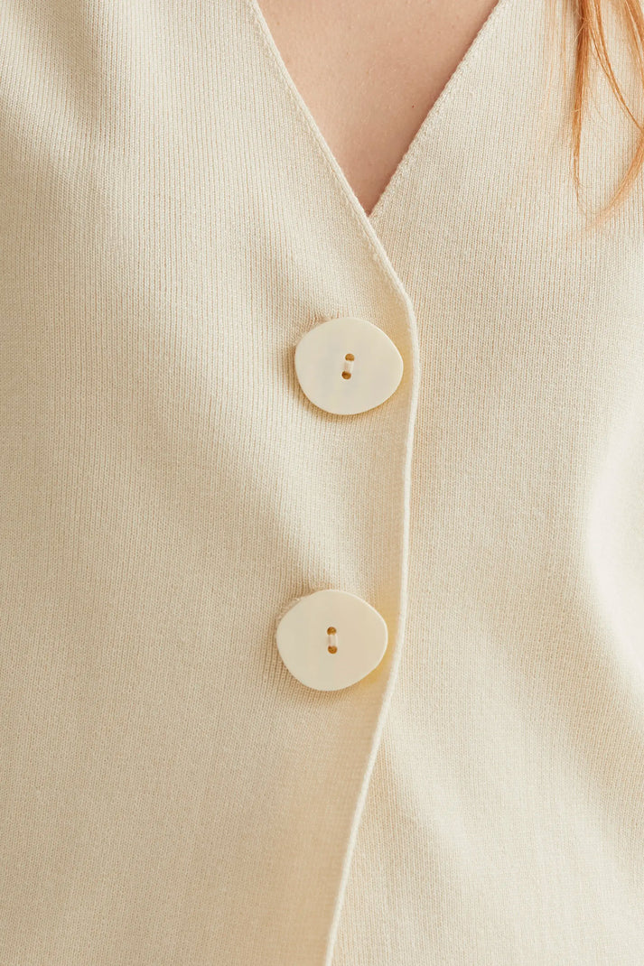 Women's neutral wrap-inspired blouse featuring an asymmetrical button-front design, soft drape and timeless boutique style.