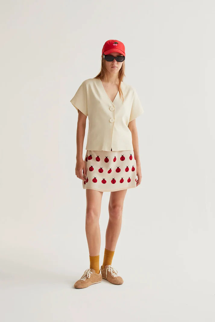 Boutique women's cream short sleeve blouse with V-neck wrap styling, oversized buttons and modern minimalist elegance.
