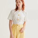 Women's white short sleeve blouse with 3D daisy flower buttons, round neckline and subtle puff shoulders for feminine spring and summer style.
