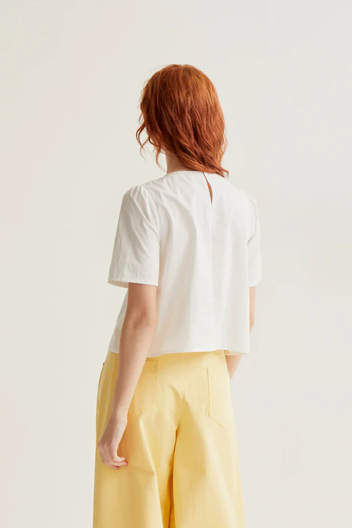 Elegant white summer blouse featuring statement daisy flower buttons, softly gathered shoulders and a lightweight tailored silhouette.