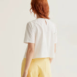 Elegant white summer blouse featuring statement daisy flower buttons, softly gathered shoulders and a lightweight tailored silhouette.