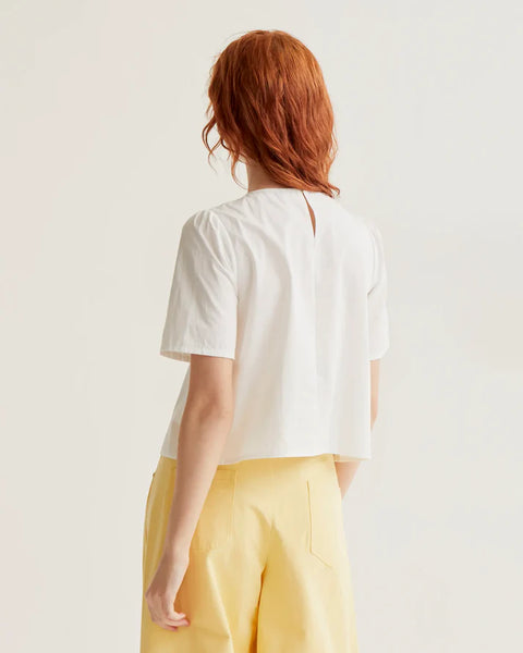Elegant white summer blouse featuring statement daisy flower buttons, softly gathered shoulders and a lightweight tailored silhouette.