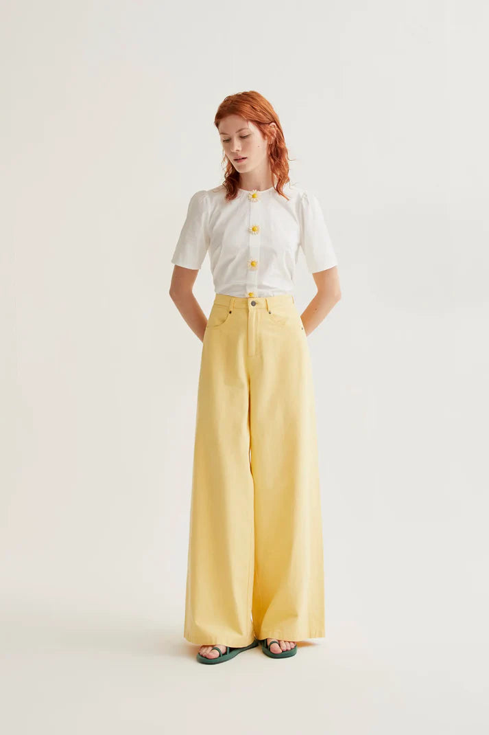 Boutique women's white short sleeve blouse featuring whimsical floral buttons and subtle puff shoulders for fresh spring and summer styling.