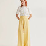 Boutique women's white short sleeve blouse featuring whimsical floral buttons and subtle puff shoulders for fresh spring and summer styling.