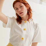 Women's elegant white floral button blouse featuring charming daisy embellishments and short sleeves for feminine spring and summer boutique style.
